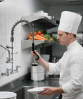 Heavy Duty Commercial Sink Faucet Wall Mount With Pre Rinse Sprayer in use by chef rinsing plates in a busy kitchen.