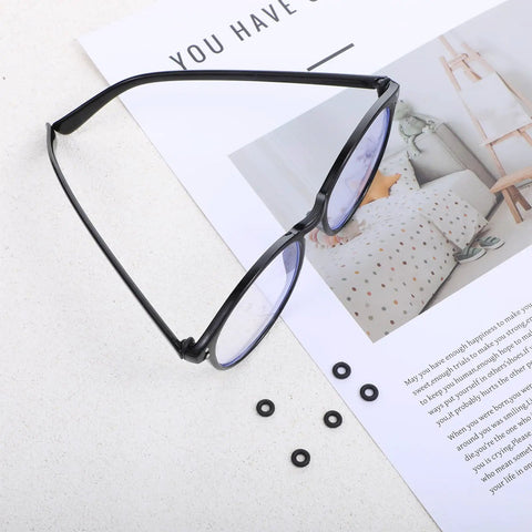 Eyeglass Repair Kit With 6 Pairs Silicone Grips Hinge Rings And Temple Tighteners Plus 3 In 1 Screwdriver For Glass Frames, showing black eyeglasses with silicone rings next to a magazine on a table.