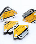 Six welding magnets with yellow labels on silver metal housings, front view for holding metal during welding.