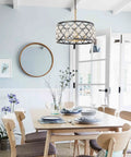 Matte black and gold crystal chandelier hanging above dining table with chairs, creating an elegant focal point in a bright room.
