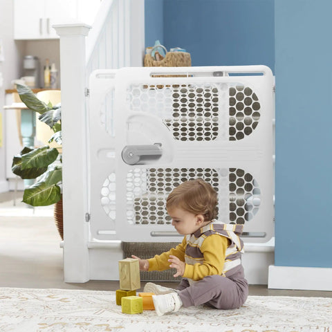 Child playing near Pressure Mounted Easy Fit Baby Gate With Memory Feature Fits 28 To 40 Inches Taupe One Hand Lock And Release.
