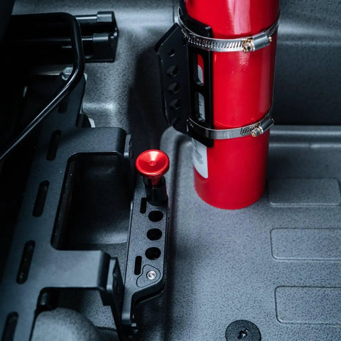 Slick Under Seat Fire Extinguisher Bracket For Ineos Grenadier Truck With One Hand Quick Release Aluminum Mount Kit And Heavy Duty Secure Ratchet Straps installed with fire extinguisher and trigger handle.