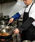 Chef wearing Heavy Duty Fireproof Welding Sleeves Heat Resistant Arm Guards while cooking in a busy kitchen.