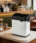 Sleek Electric Portafilter Cleaner With Auto Espresso Knock Box and Hella Fast Filter Handle Scrubbing on a café counter.