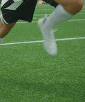 Athlete wearing Stealth Lace-Free Ankle Brace for left or right ankles, ultra lightweight support with flex-support stays, running on field.