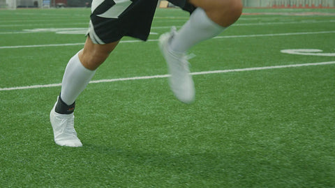 Athlete wearing Stealth Lace-Free Ankle Brace for left or right ankles, ultra lightweight support with flex-support stays, running on field.