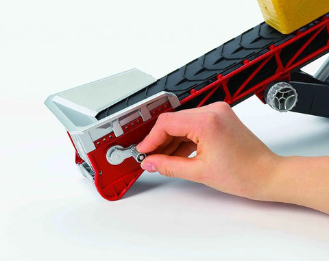 Close-up of hand operating 1 16 Scale German Made Hand Crank Conveyor Belt Toy Model with height adjustable chassis and V-shaped striped belt.