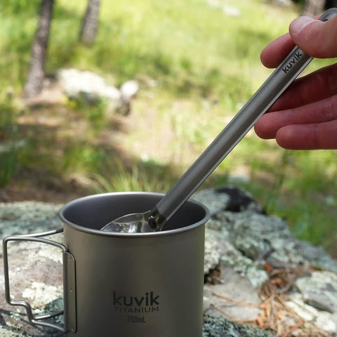 Featherweight Titanium Spoon Set For Backpacking And Camping in a cup outdoors, showcasing ultra compact eight point five inch utensil.