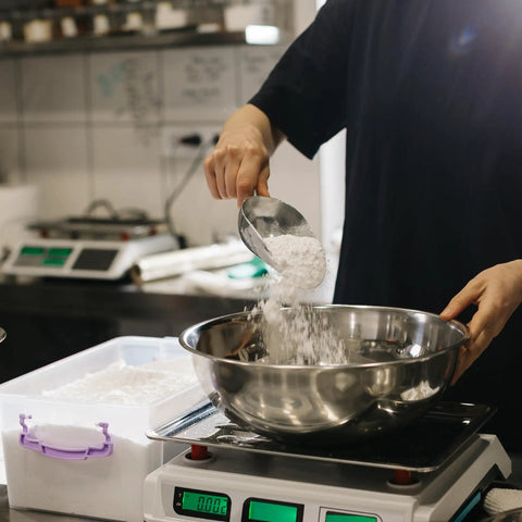 Person measuring Calcium Sulfate 1 Gallon Bucket Pro Grade Anticaking And PH Regulator Thickener Plaster Additive in a metal bowl
