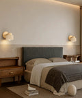 IPEDWO Yellow Travertine Wall Sconce with Natural Wood,4.7" Single Sconce mounted on a bedroom wall beside a bed.