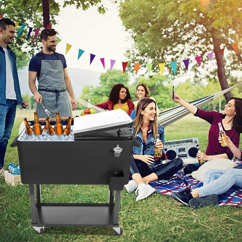 80 Quart Rolling Cooler Cart On Wheels With Dual Tops Built In Bottle Opener And Cap Catch Handy Shelf Portable Bar For Outdoor Patio Party And Backyard BBQ Ready In Black Keeps Ice Cold Up To 48 Hours With Ice Sheet in use at a picnic with people.