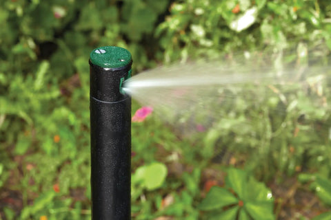 Gear Drive Rotor Shrub Sprinkler With Adjustable Arc Range And 25 Foot Reach spraying water in a garden setting.