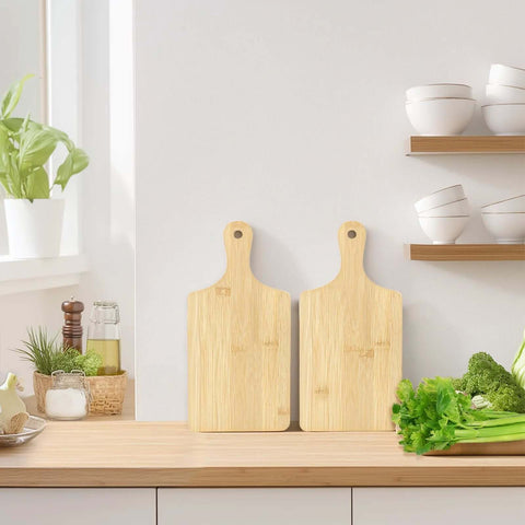 Two bamboo cutting boards with handles shown in front view on a wooden kitchen counter, 11x5 inches.