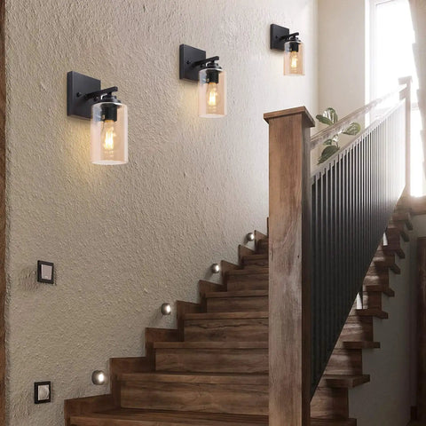 Three rustic oil rubbed bronze wall light sconces with amber glass shades along a wooden staircase, warm ambient glow, up mount.