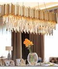 Top Shelf K9 Crystal Pendant Light With Polished Gold Metal Bar And Warm E14 Led Bulbs Perfect For Dining Rooms Or Cafes Quick Mount And Instant Home Glow Up hanging above a dining table.
