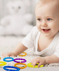 Infant playing on carpet with 24 Colorful Teething Ring Links For Babies Plastic Chain Toy Set For Strollers, Car Seats, And Cribs