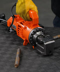 Benner Nawman Dc-20Wh Portable Heavy-Duty Rebar Cutter shown with a gloved hand, cutting rebar on a textured surface.