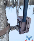 Versatile Trail Camera Mount For Moultrie Edge Models 2 And 3 Solar on tree with strap in snowy forest.