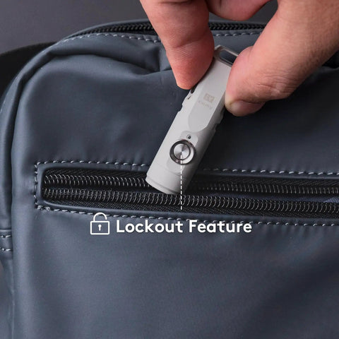 Hand placing Keychain EDC Flashlight Red USB C 650 Lumens Ultra Compact Aluminum Alloy Torch with lockout feature into bag pocket