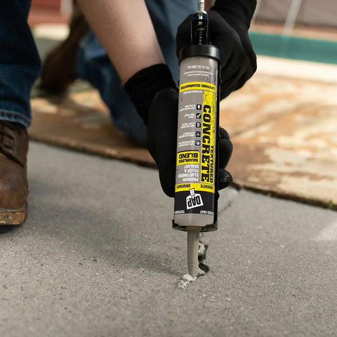 Man applying Textured Concrete Premium Elastomeric Filler And Sealant For Crack Repair In Interior And Exterior Concrete And Masonry, Waterproof And Weatherproof, Ready To Use, Gray, 10.1 Oz to a concrete crack.
