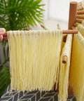 Foldable Wooden Pasta Drying Rack For Fresh Homemade Noodles displaying fresh noodles on wooden rods in kitchen setting.