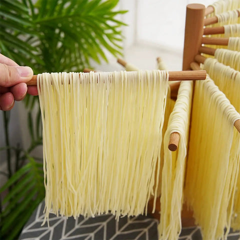 Foldable Wooden Pasta Drying Rack For Fresh Homemade Noodles displaying fresh noodles on wooden rods in kitchen setting.