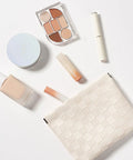 Leather Cosmetic Pouch For Purse With Secure Snap Closure And Slim Profile with makeup products arranged on a white surface.