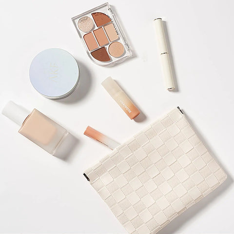 Leather Cosmetic Pouch For Purse With Secure Snap Closure And Slim Profile with makeup products arranged on a white surface.
