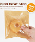 100 Pack Heat Sealable Cookie Bags With Window Grease Resistant Grab And Go Bakery Bags, hand holding bag with donut inside