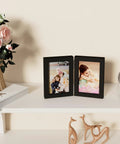 Double 4x6 Picture Frame Vertical From Engineered Wood With Plexiglass Bifold Photo Frame For Tabletop Display Holds Two 4x6 Photos In A Dope Black Finish That Fits Any Desk Or Shelf on a white shelf with decor items.