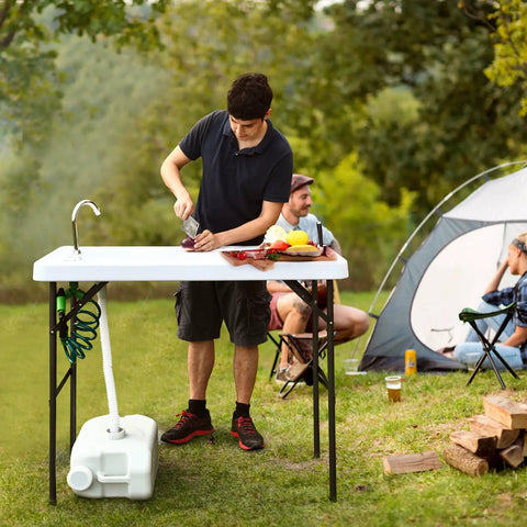 Person using Portable Outdoor Fish Cleaning Table with Sink and Sprayer, folding design with steel frame at campsite