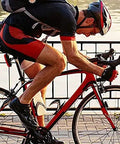 Cyclist riding by a lakeside, wearing helmet and sports gear, showcasing Assioma Duo Upgraded Double Sided Power Meter Pedals Waterproof.