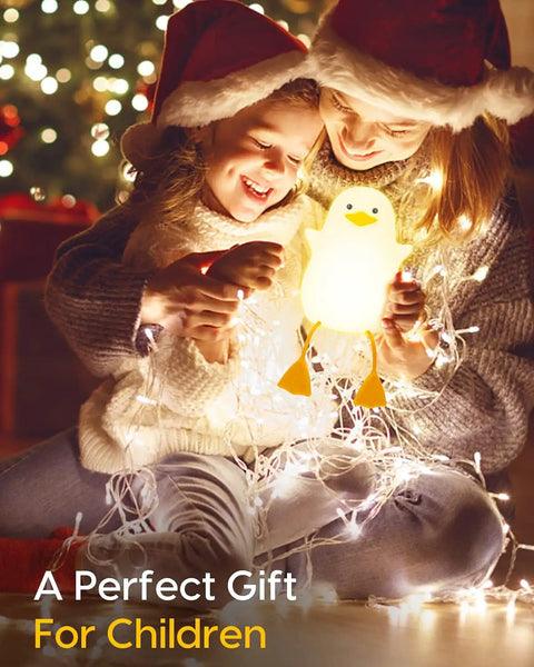 Children holding Squishy Duck Night Light For Kids With Soft Warm Glow Silicone Dimmable Nursery Lamp Rechargeable LED Battery 20 Minute Timer And Tap Control Perfect Bedtime Helper For Toddler Bedrooms And Cute Kids Decor, surrounded by holiday lights.