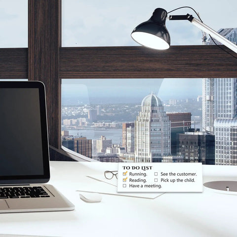 Desk with laptop, lamp, glasses, and a to-do list against city skyline view