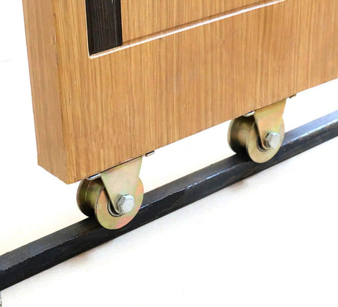 Straight Up Heavy Duty Galvanized Steel Track Wheel Featuring Rock Solid Double Bearings For Slick Sliding Gate Roller And No Junk Barn Door Caster On 50 Millimeter Wire Rope Rails attached to wooden panel on black track.