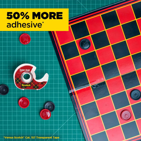 Super Hold Tape With 50 Percent More Adhesive, Clear Finish, 2 Rolls, Dispenser Ready next to checkers board on green grid mat