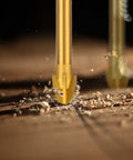 Masonry drill bits set, 1/4 in size, titanium-coated carbide tips, gold color, close-up with wood shavings (2 bits shown)