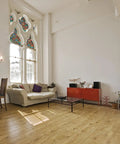 Modern living room with large stained glass windows featuring a colorful pattern, wooden flooring, and contemporary furniture.