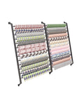 Heavy Duty Wall Mount Fabric Roll Storage Rack With Quick Snap Crossbars To Keep Your Wrapping Paper Ribbons And Craft Spools Totally Sorted And No Mess At All, displaying neatly organized rolls of patterned wrapping paper.
