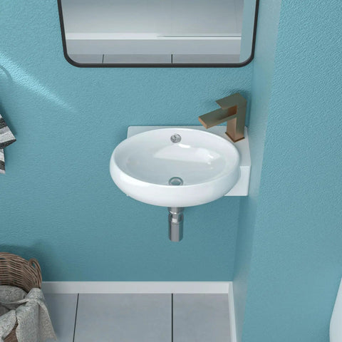 Small round white ceramic bathroom sink with modern faucet on turquoise wall background