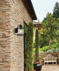 Oil Rubbed Bronze Outdoor Indoor Wall Sconce With Seeded Glass Shade installed on stone wall in rustic garden patio setting.
