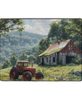 Vintage tractor beside an old barn in a lush green rural landscape under a cloudy sky