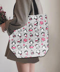 Person holding a tote bag with penguin and heart design.