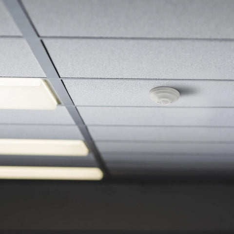 Ceiling Mount 360 Degree PIR Occupancy Sensor for Indoor Lighting installed on a white ceiling panel, up to 15 ft high, 120-277V.