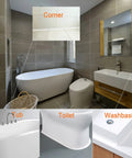 Bathroom with three white fixtures: freestanding tub, toilet, and sink with wooden vanity; gray tile walls.