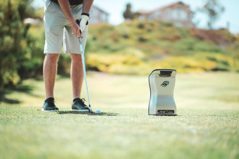 Golfer using GCQuad Golf Launch Monitor with Quadrascopic Four Camera System for precise ball and club head data, outdoor use