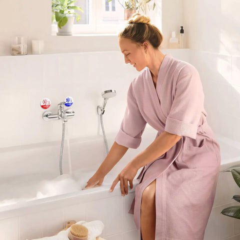Woman in pink robe using a bathtub faucet with 6 Pack Hella Durable Hot And Cold Water Faucet Labels Self Adhesive Waterproof Sink Temperature Stickers.
