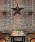 Rustic Metal Barn Star Wall Decor Made From Recycled Iron hung on a brick wall in a farmhouse-style setting with outdoor seating.