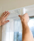 Applying Max Strength Window Insulation Kit For Cold Weather, No-Fuss, Heavy Duty Shrink Film on window frame indoors
