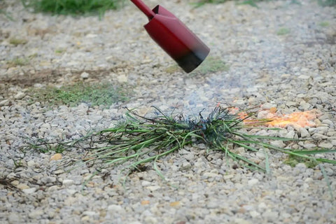 Vapor Torch Kit With Squeeze Valve And Adjustable Pilot 500,000 BTU Propane Weed Burner in use on gravel surface